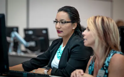 student at a computer talking to an instructor