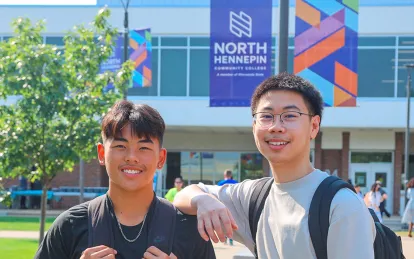 two students outside with nhcc banners and buildings in the background 