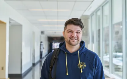 male student smiling in a hallway