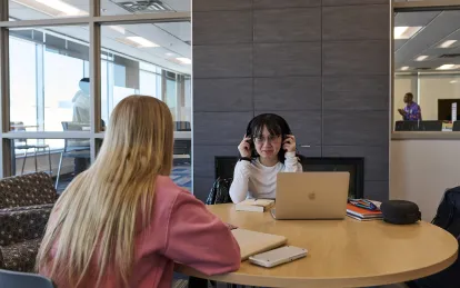 two students sitting at a table in a lounge
