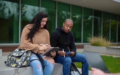 two students sitting outside talking