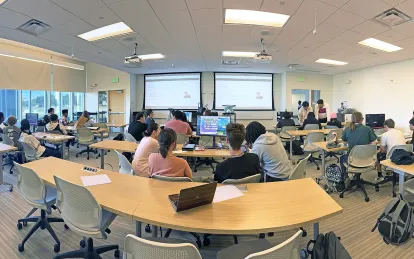 students in large classroom working on laptops
