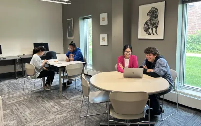 four people sitting at tables in a room with windows