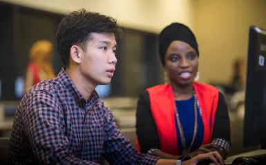 Male and female student looking at the same computer