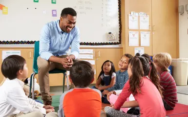 male teacher surrounded by elementary students 