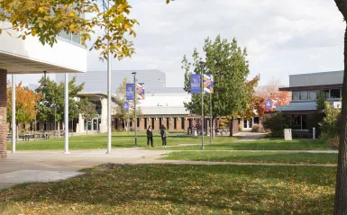 two students standing in the courtyard in the fall 