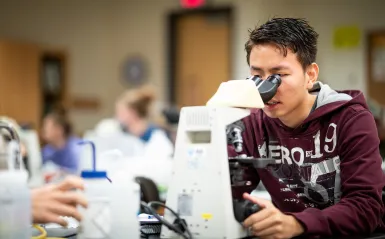 Biology student using microscope 