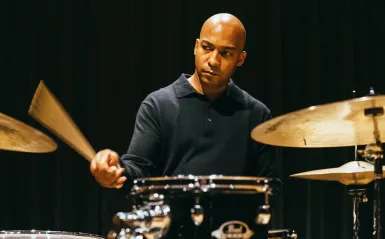 An image of drummer Adonis Rose playing on a drum kit.