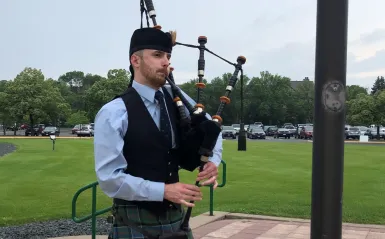 man in a kilt playing a bagpipe outside 