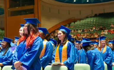 students wearing caps and gowns in the commencement hall