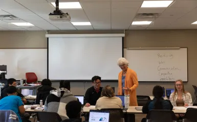students in a classroom talking with an instructor 