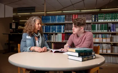 student sitting at a table talking with an advisor 