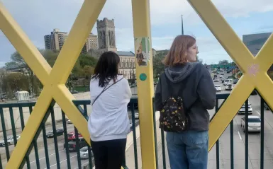 two people looking off in the distance from a bridge