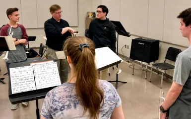 students talking with an instructor in a music classroom 
