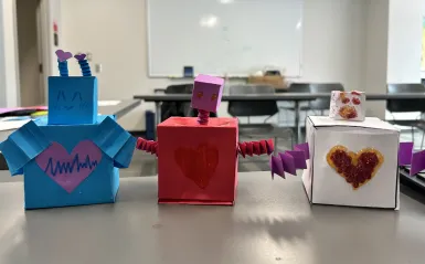 3 small, crafted robots with hearts in the center