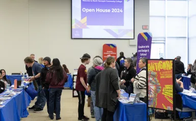 people walking around a large room and talking to people at tables 