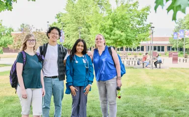 four students standing outside on a sunny day