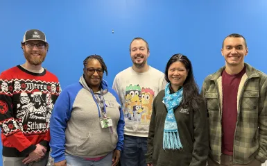 Staff from the Office of Student Life standing together in front of a blue wall