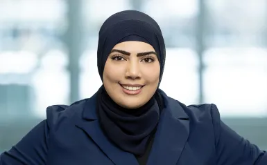 student standing in a hallway with her hands on her hips smiling. 