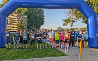 a large group of runners standing under inflatable arches. 