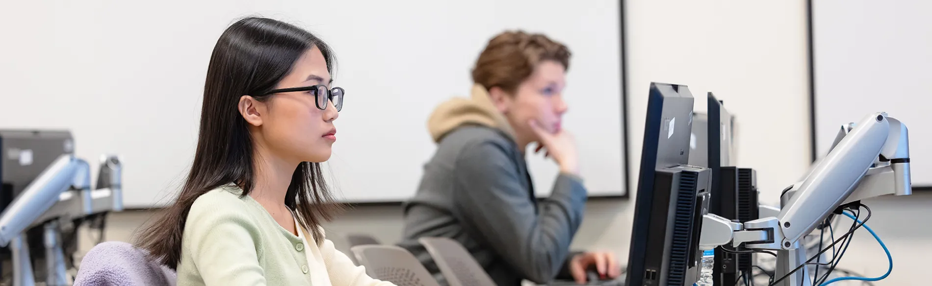 two students at computers in a classroom 