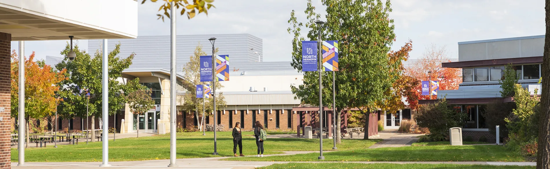 two students standing in the courtyard in the fall 