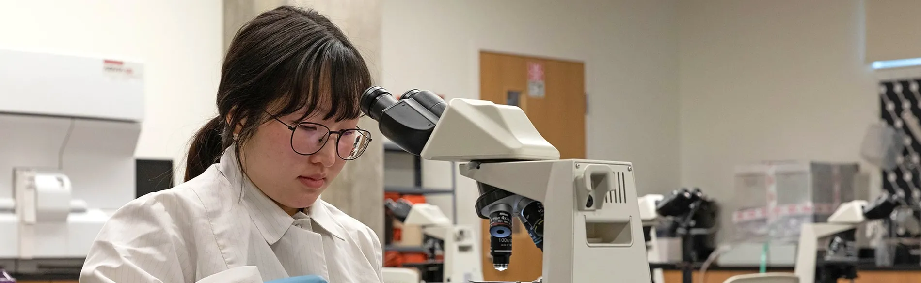 female student working with a microscope