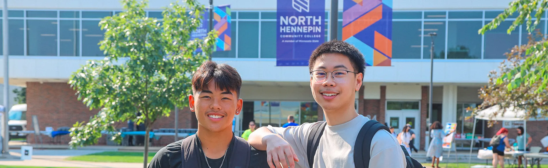 two students outside with nhcc banners and buildings in the background 