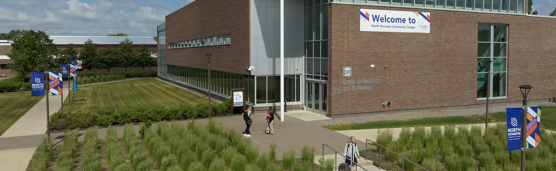 students walking on campus by a big building on a sunny day