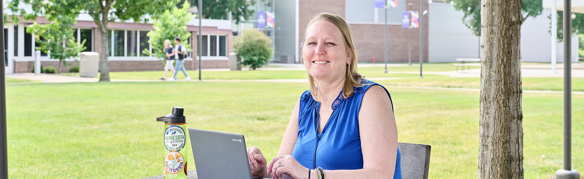 woman sitting at a table outside with a laptop 