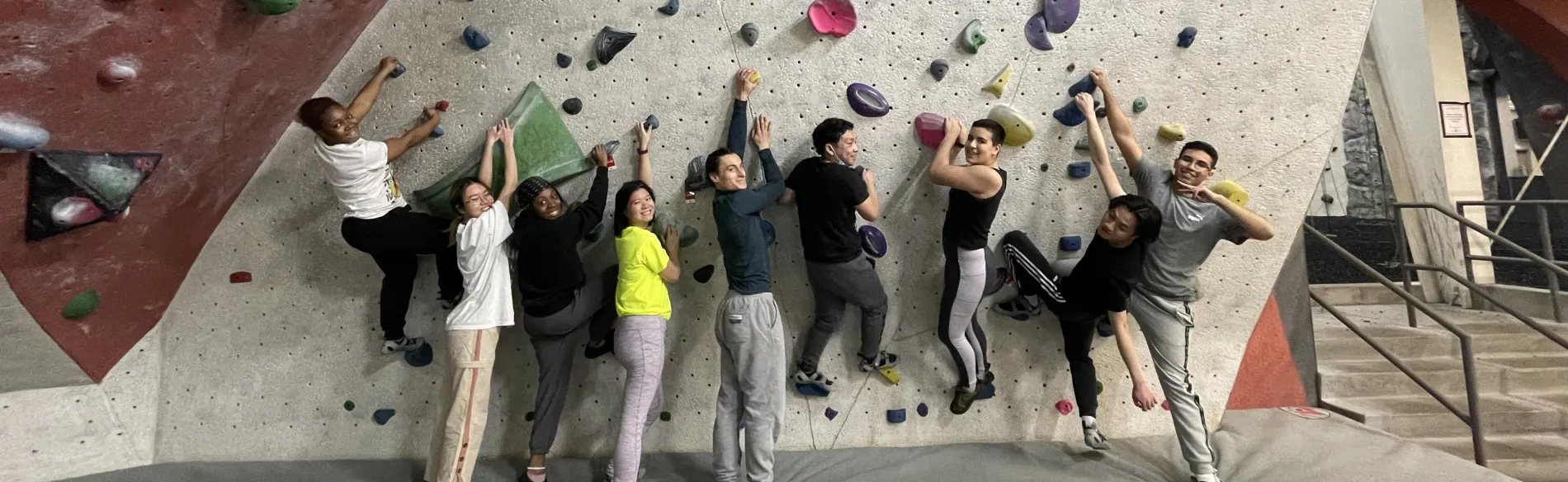 group photo in front of rock climbing wall