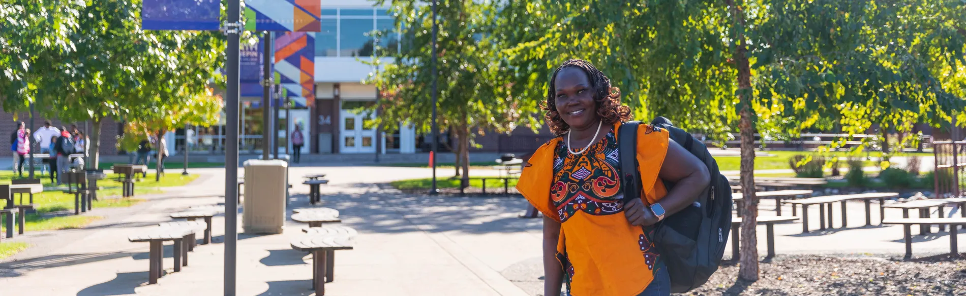 student with backpack smiling outside on sunny day