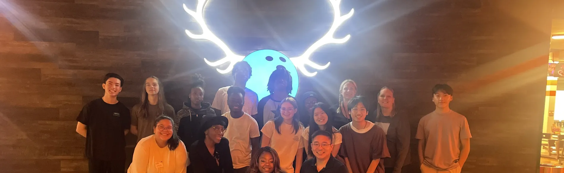 group photo in front of neon bowling sign