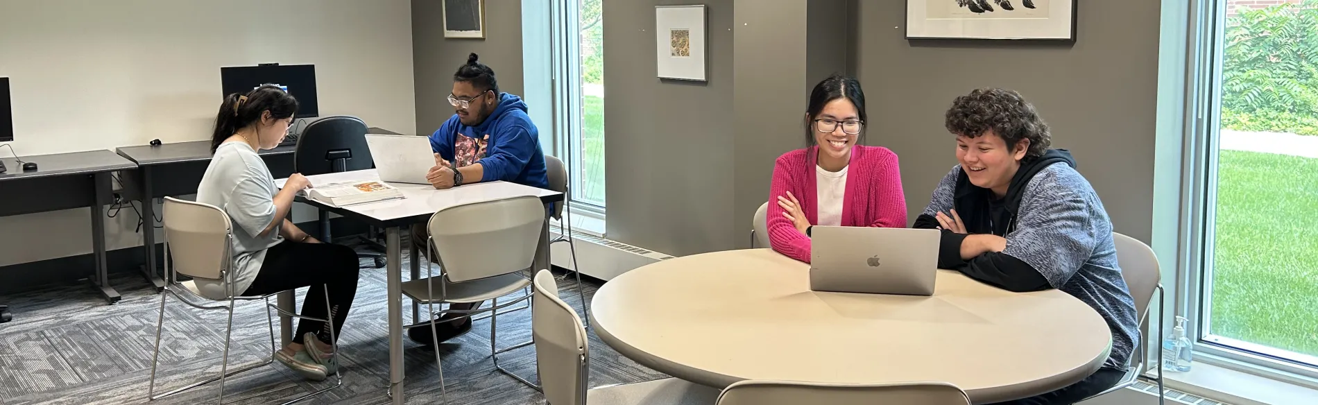 four people sitting at tables in a room with windows