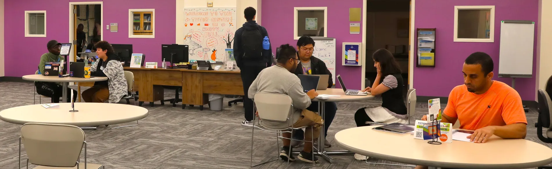 people sitting at tables in a large room with purple walls
