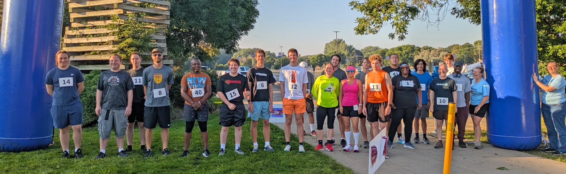 a large group of runners standing under inflatable arches. 