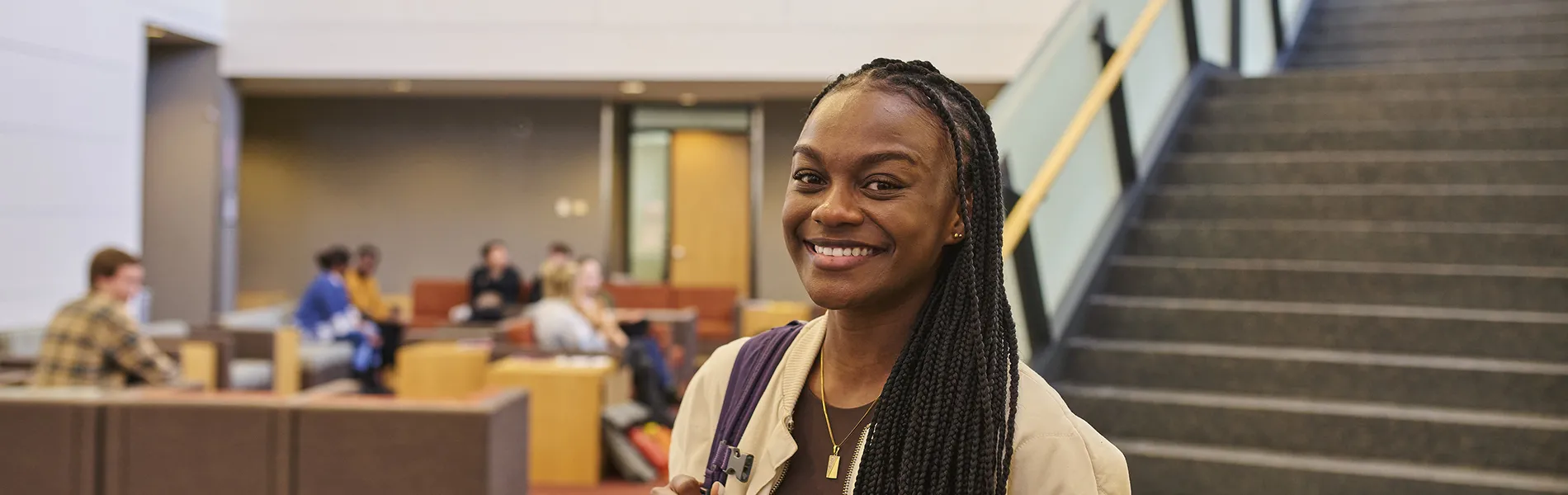 student smiling wearing a backpack with students in the background