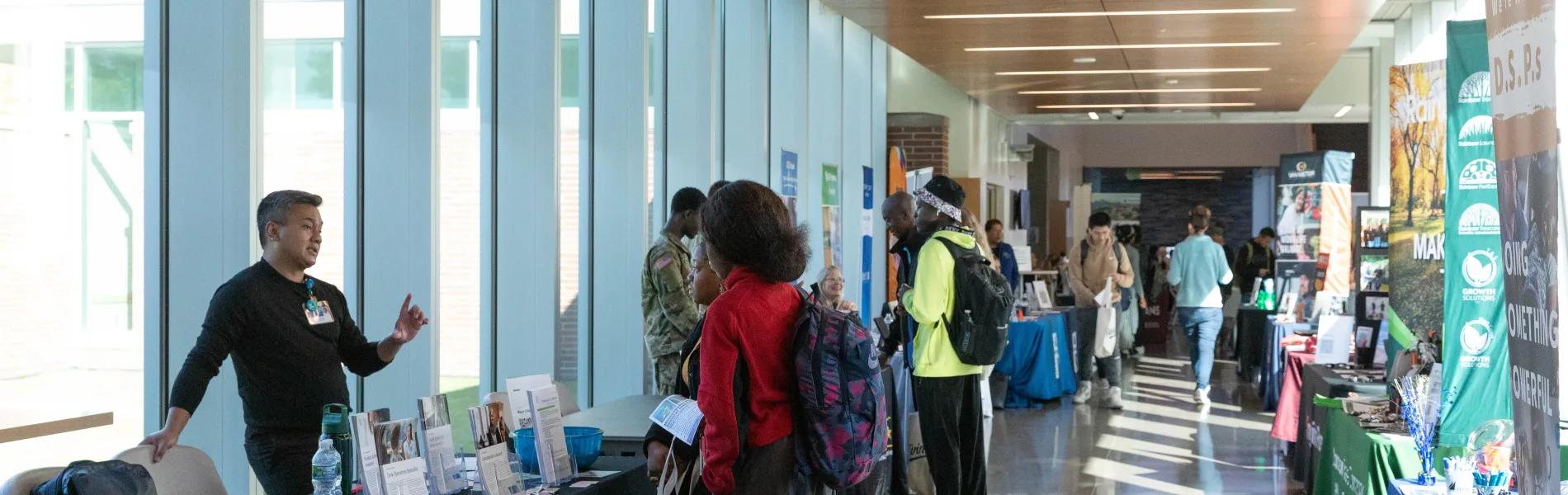 students in a hallway talking to people at tables