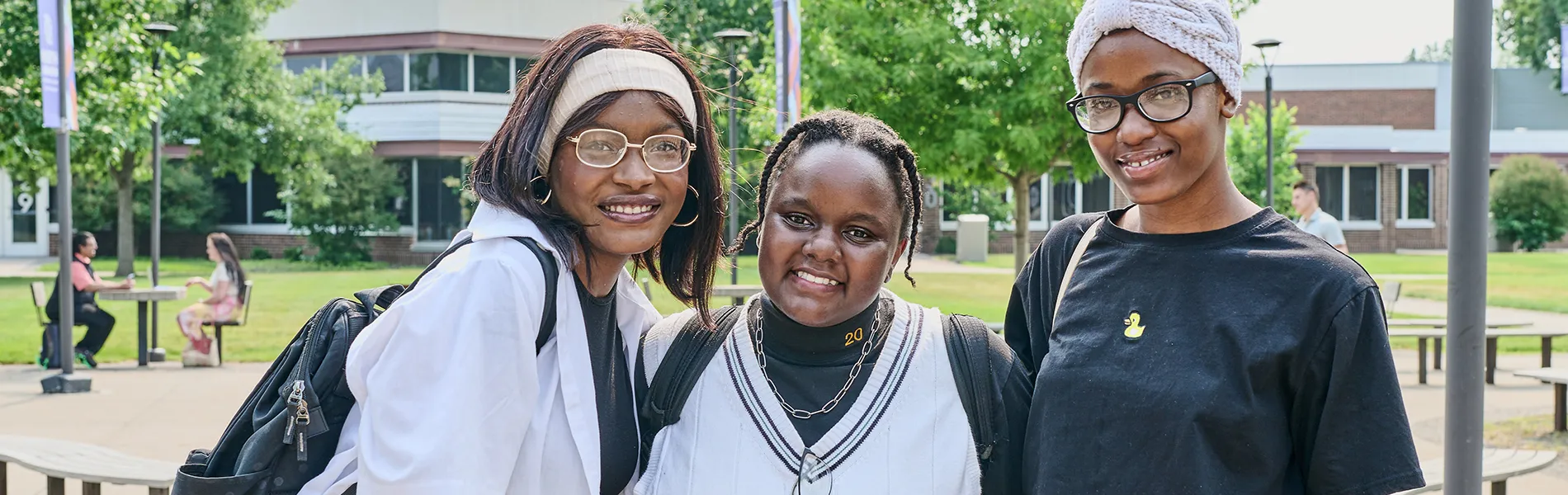 three students smiling outside