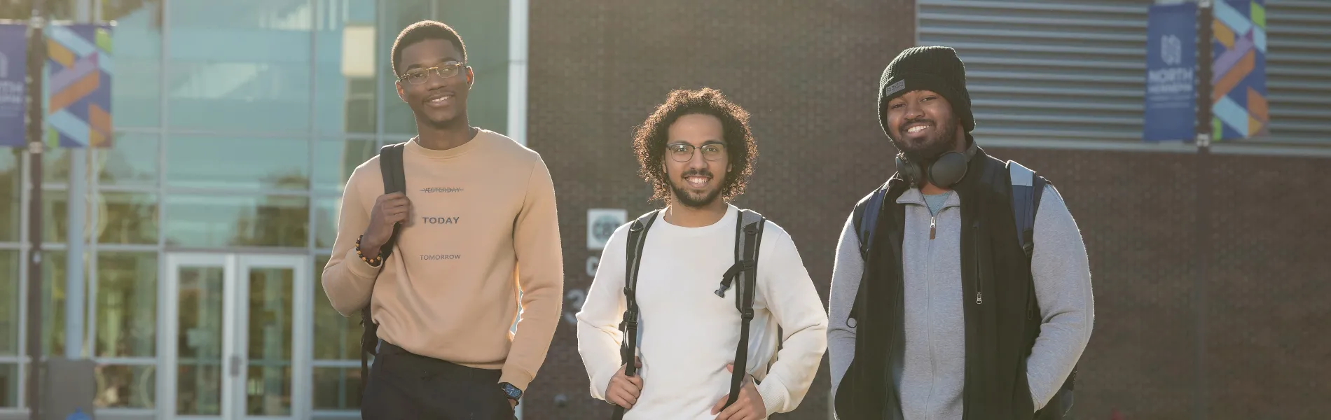 three male students standing outside on a sunny day