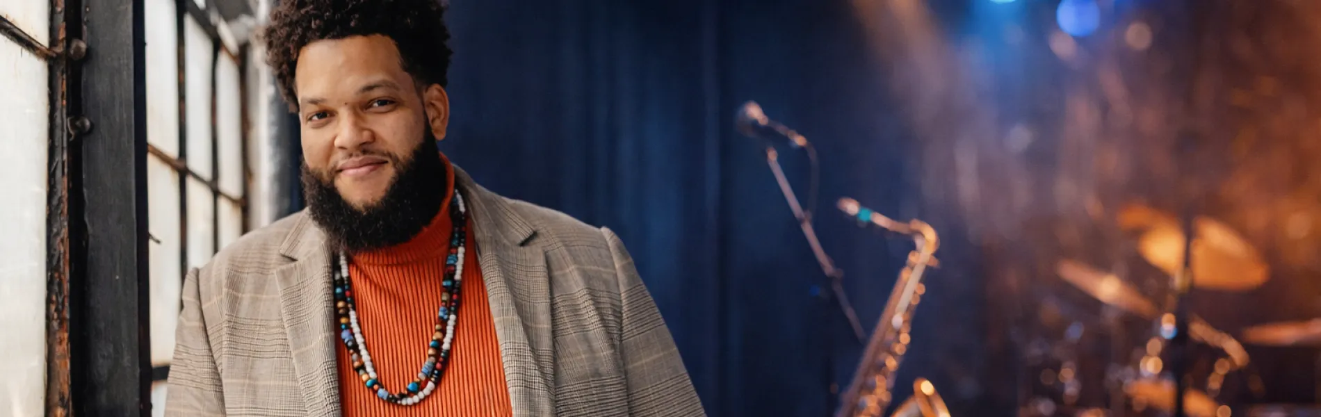 man standing with a trumpet with instruments in the background