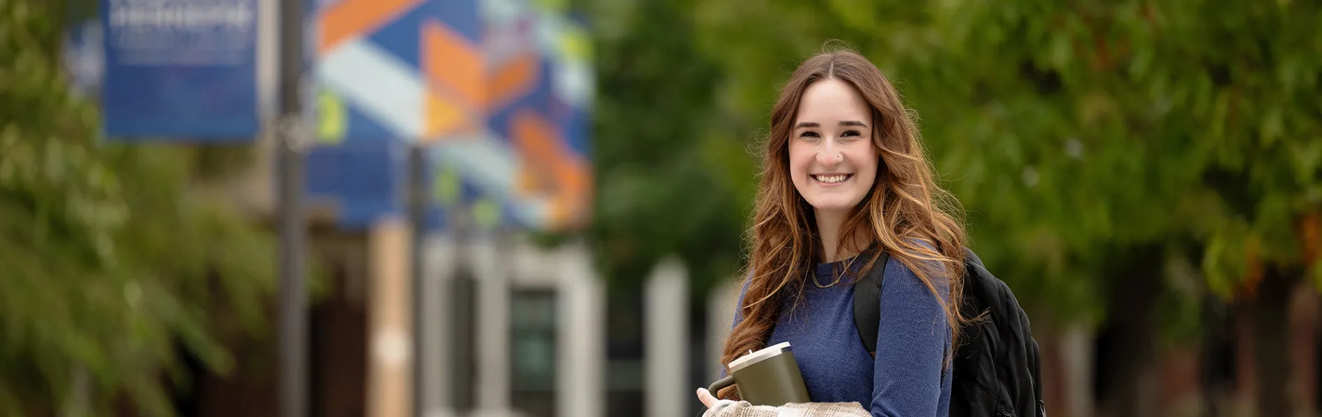 student with a back pack outside smiling