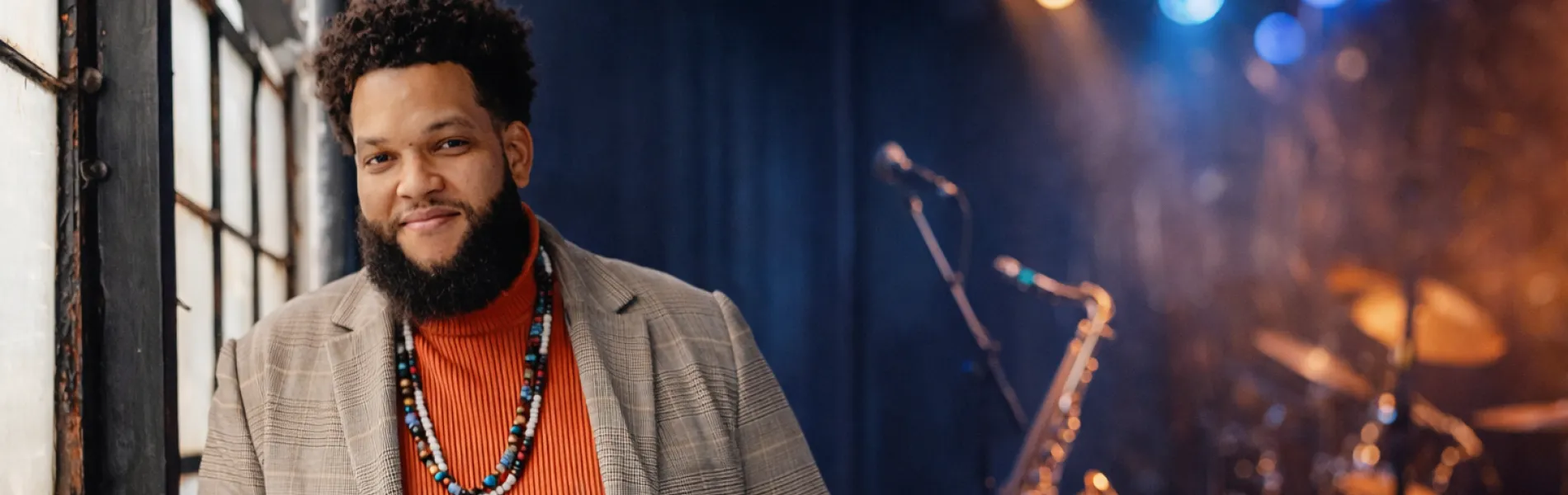 man standing with a trumpet with instruments in the background