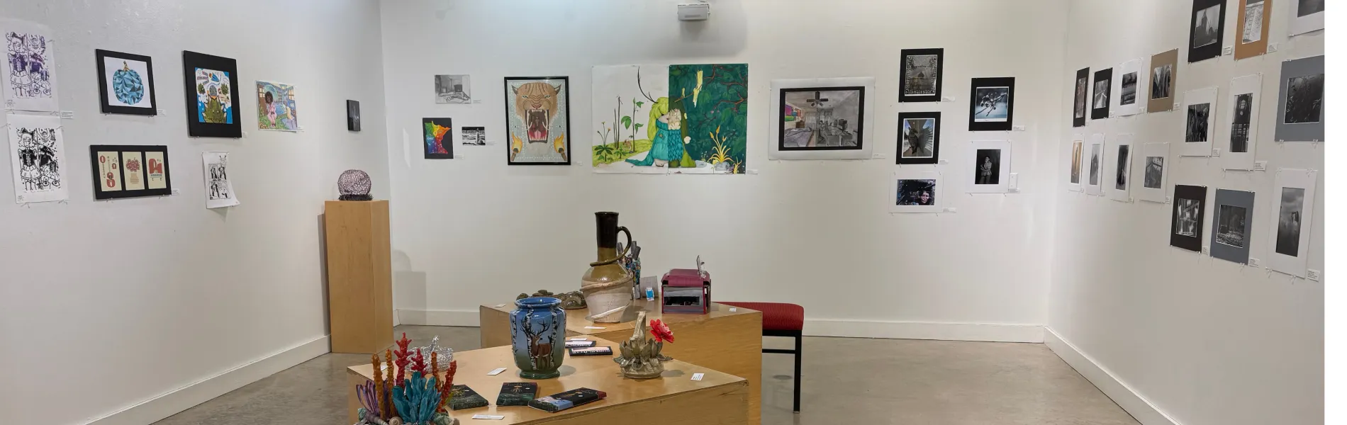 Student art hanging on walls and 3-D art displayed on tables. 