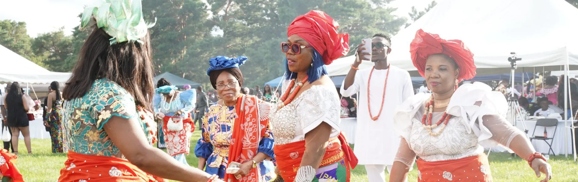 A group of women wearing colorful dresses dancing outside. 
