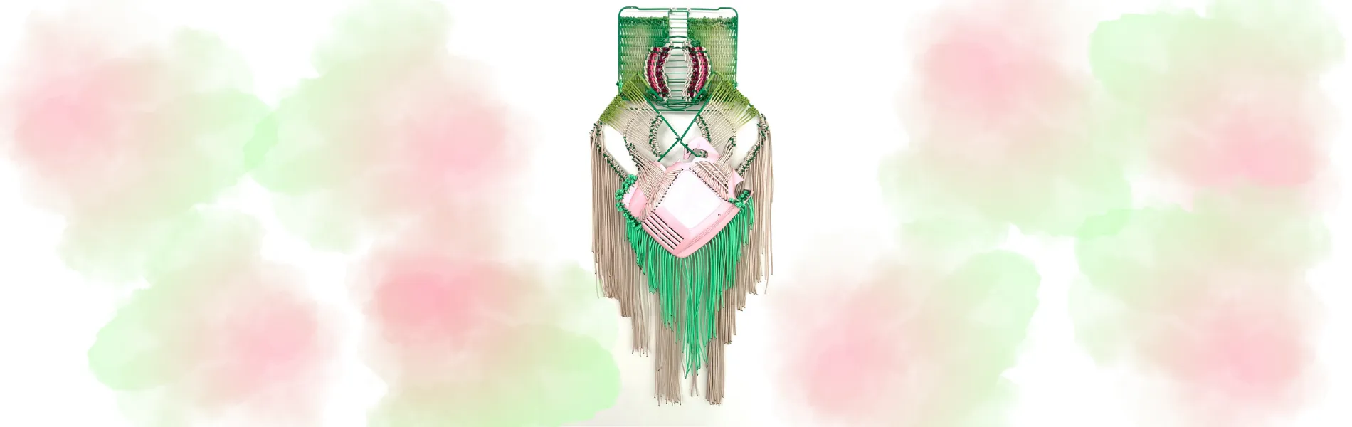 green, pink, and brown weaved art piece on a background of white, pink, and green. 