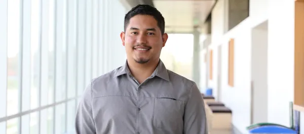 male student smiling in hall by windows