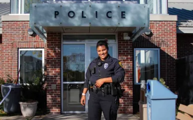 female alumni cop standing outside police station