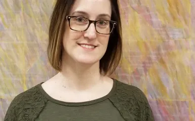 female student standing in front of a colorful piece of art