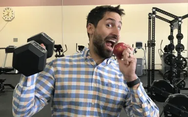 faculty member lifting a weight and eating an apple 